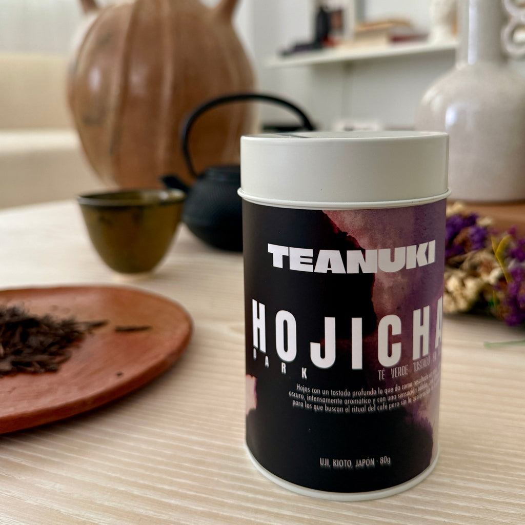 Teanuki Hojicha dark roast tea canister on a table with decorative items in the background