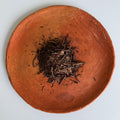 Dark roast hojicha Japansese green tea leaves from Teanuki on a terra cotta plate. 
