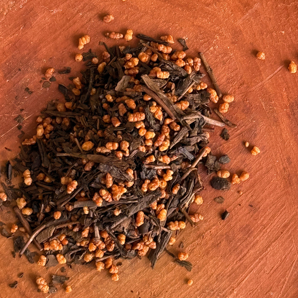 Roasted Hojicha Green Tea leaves and roasted Japanese genmai toasted rice on a terra cotta surface