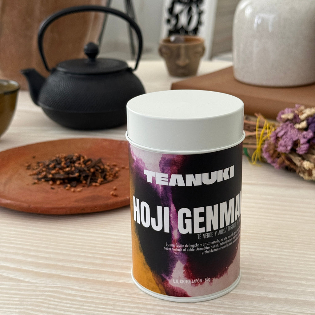 Tea canister with 'Teanuki' branding on a wooden surface with roasted green tea leaves and Japanese Genmai behind it. 