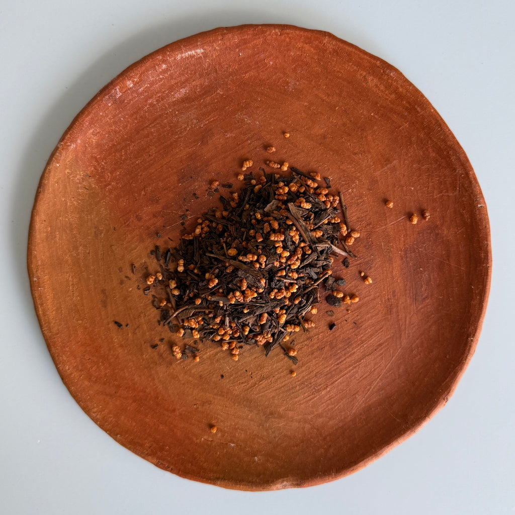A terra cotta plate with roasted Japanese green tea leaves, hojicha, and roasted rice, genmai. A tea blend from Teanuki.