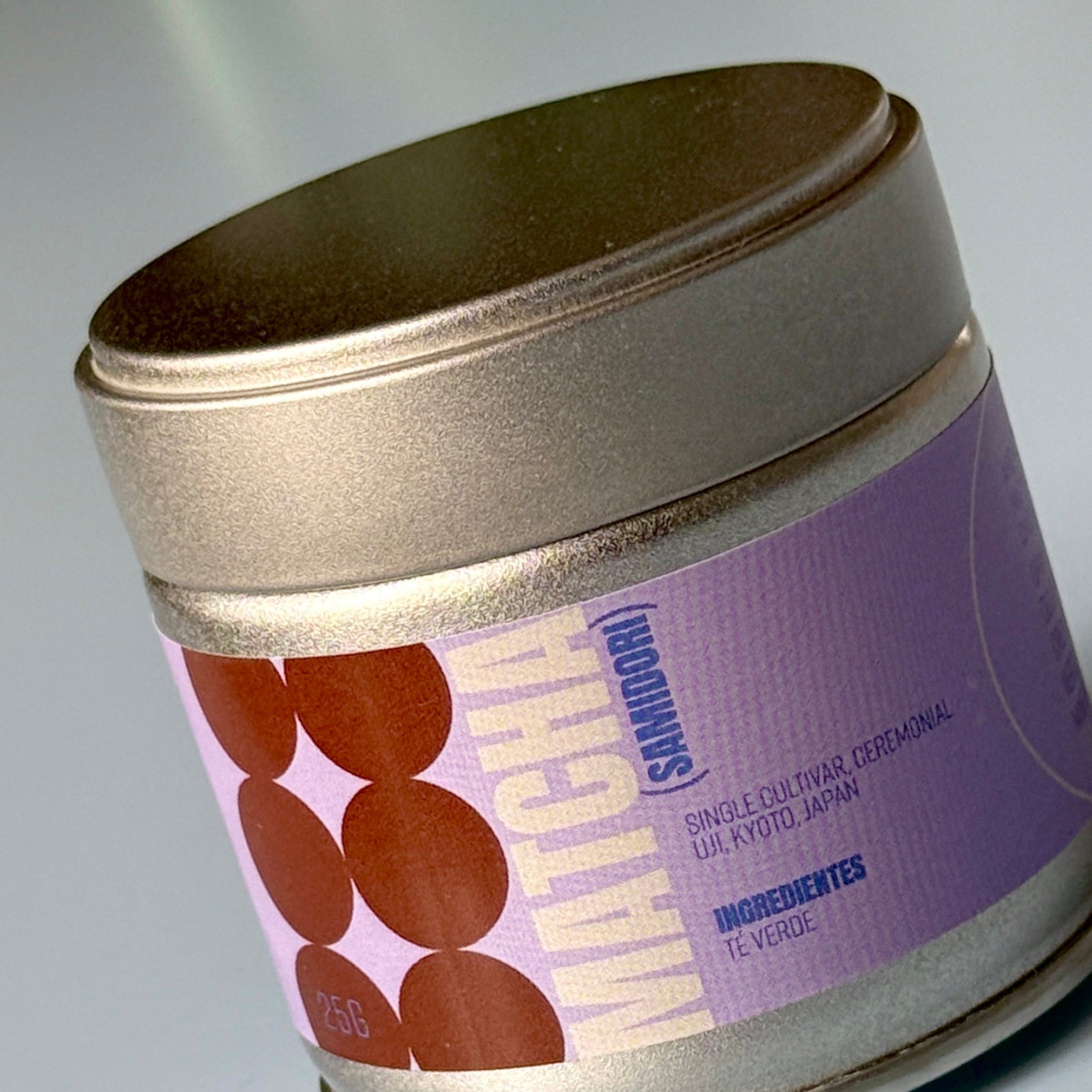 Silver matcha tin with a purple label featuring brown circles on a gray background